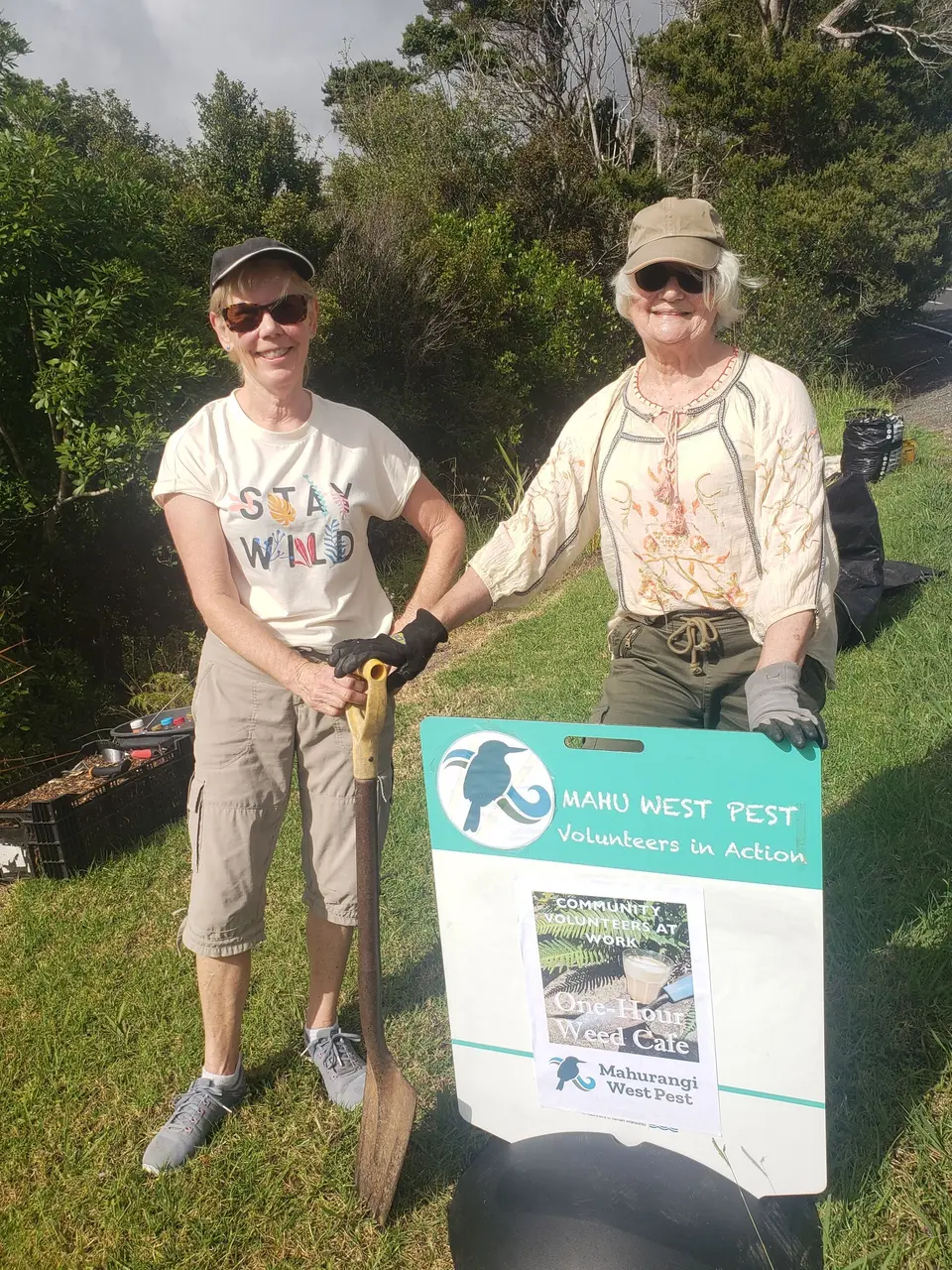 Two volunteers holding pulled weeds at a weed café